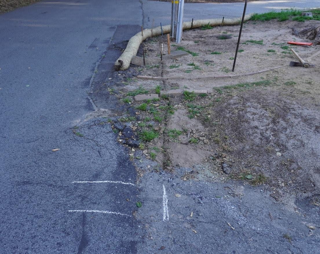 Cracked road edge and eroded dirt around the pole before repairs began
